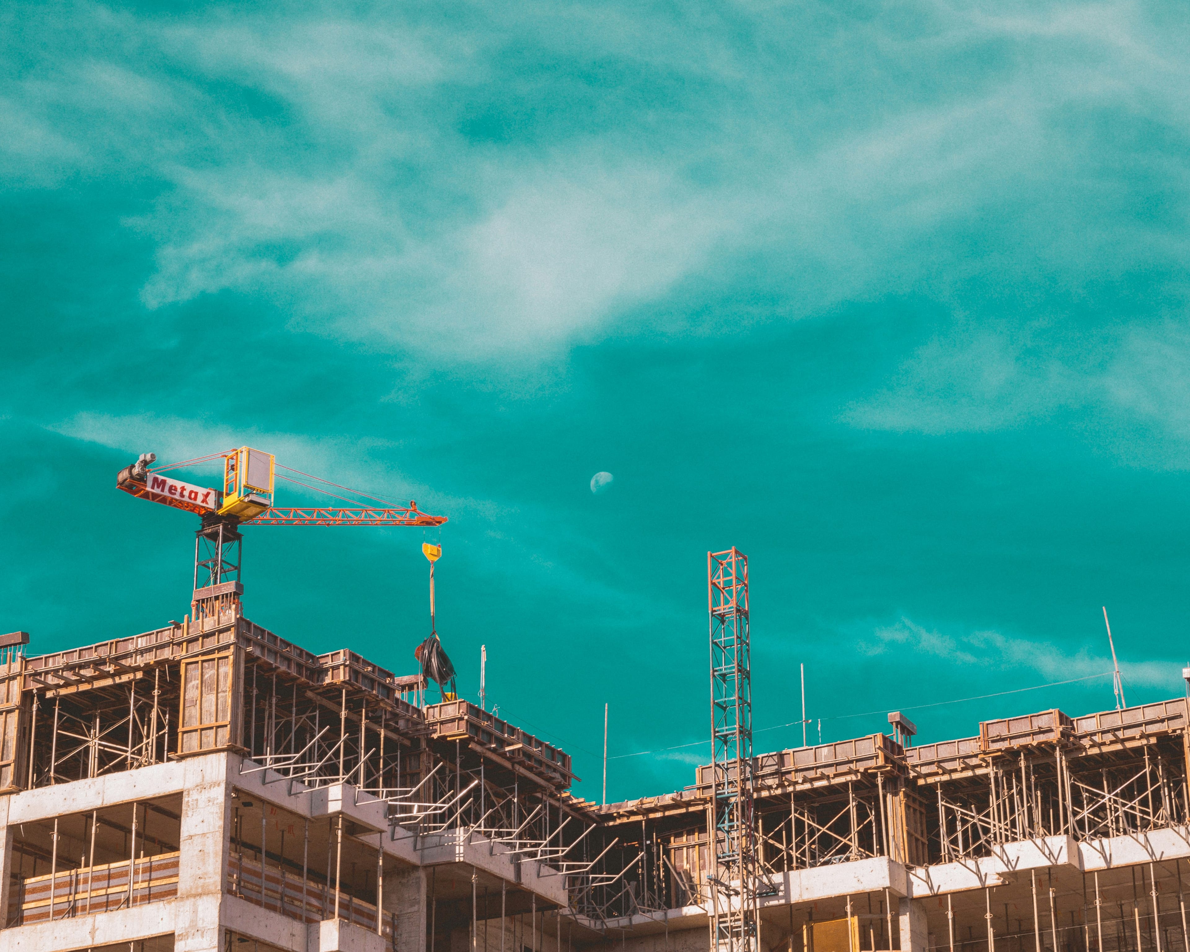 Building under construction with tower crane, civil works in progress.