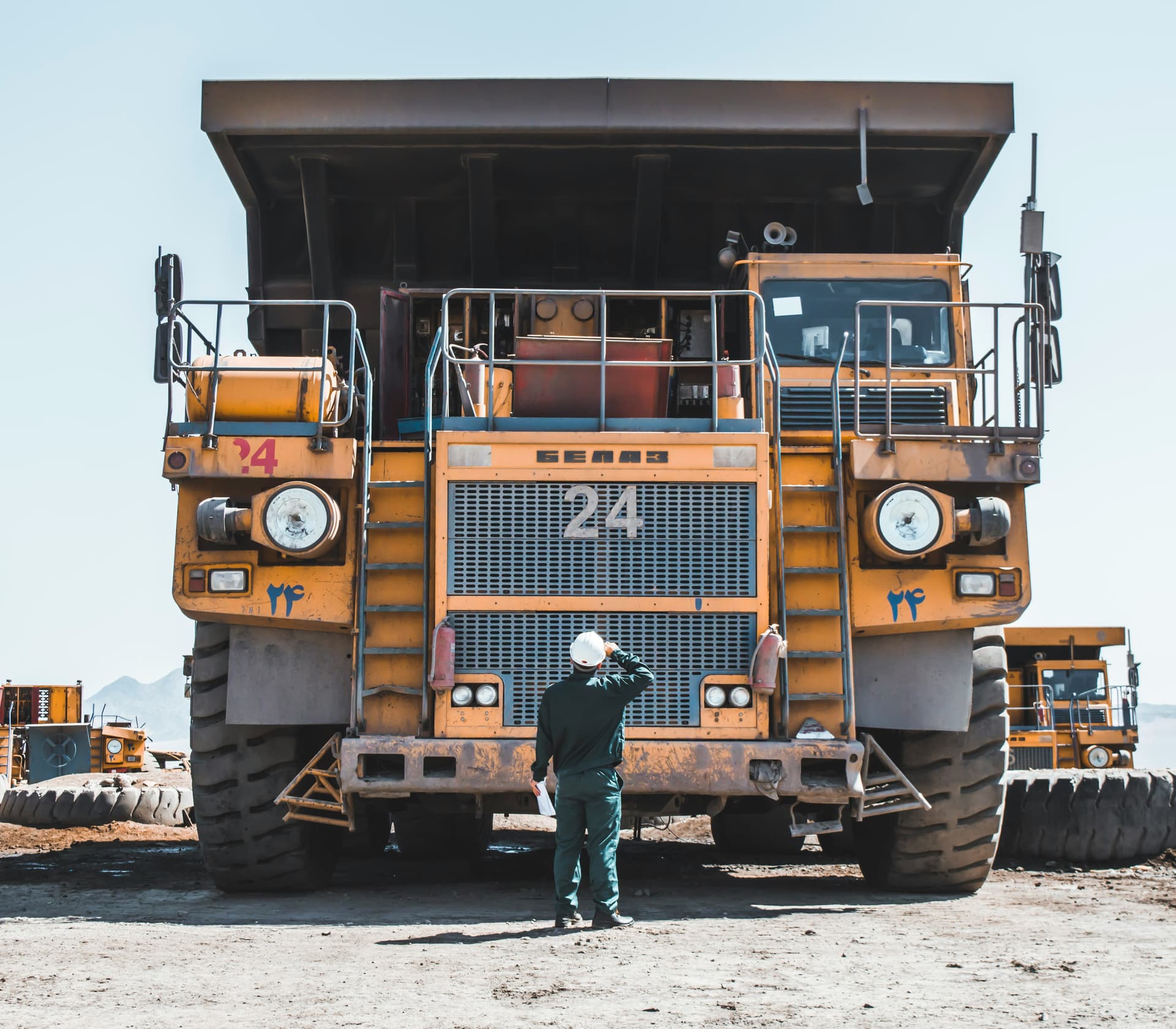 Mining haul truck on a Guinean operation, operator visible in front for scale.